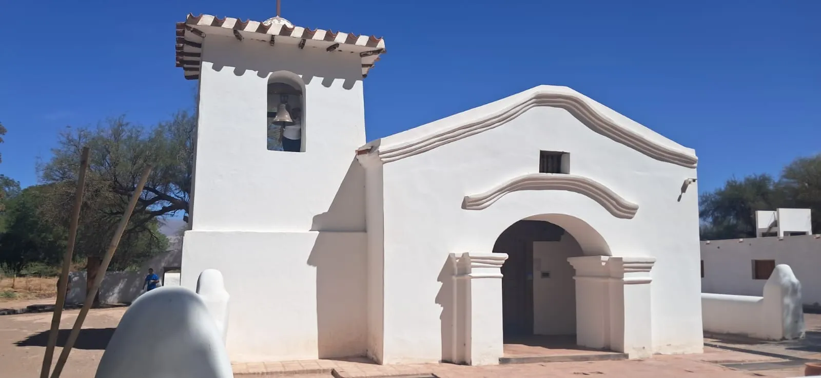 Fachada blanca de la Iglesia de San Pedro, con su campanario, bajo un cielo azul