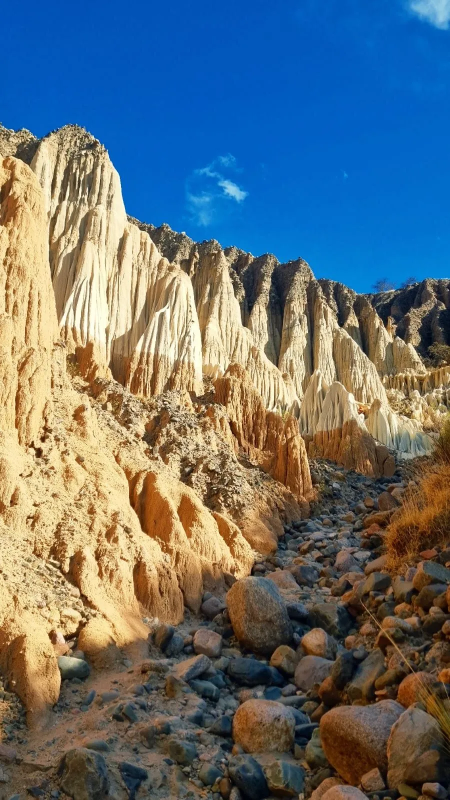 Torres de roca clara y anaranjada talladas por la erosión sobre una quebrada de piedras, con cielo azul