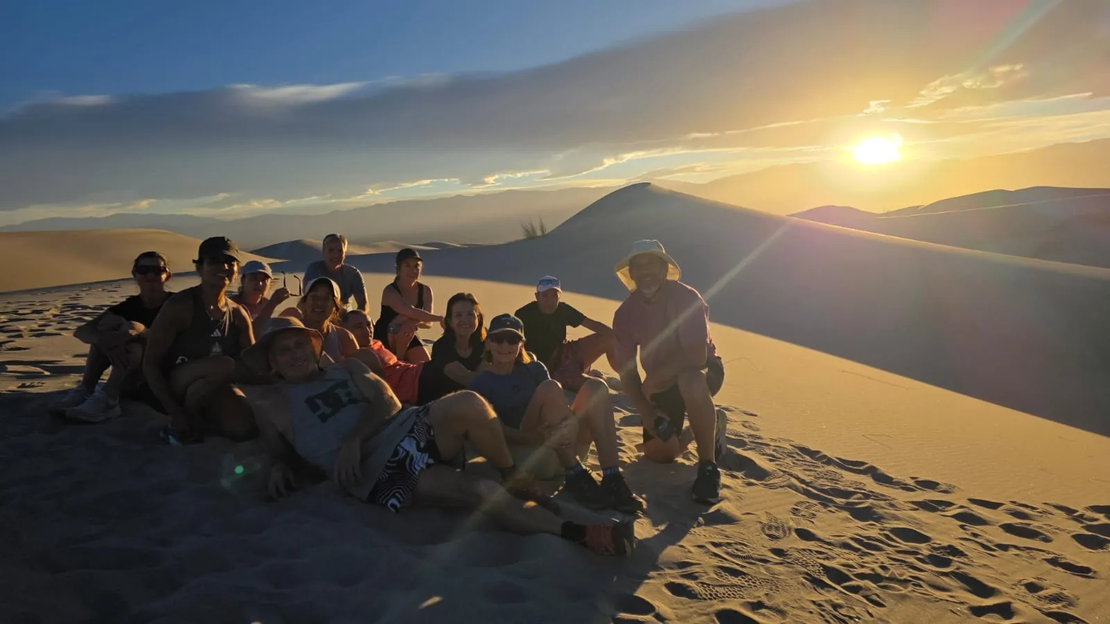 Un grupo sentado sobre una duna a contraluz del atardecer