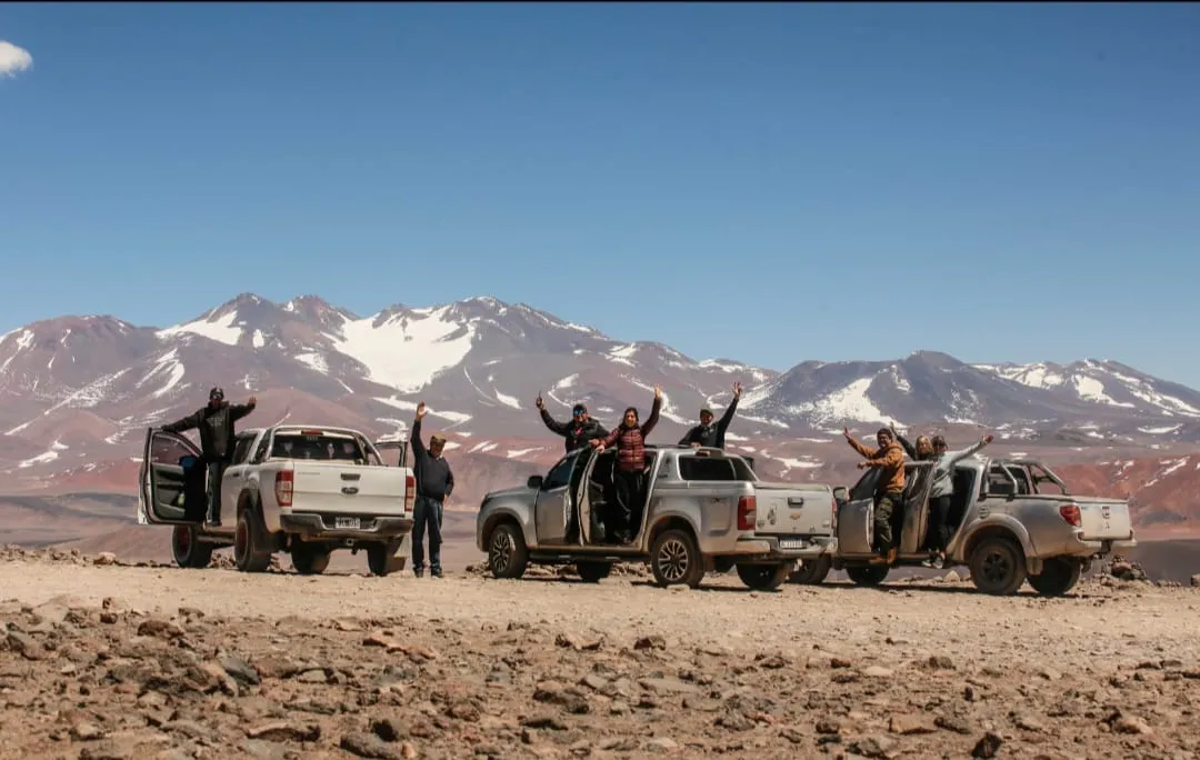 Tres camionetas 4x4 con pasajeros frente a montañas con nieve en la puna