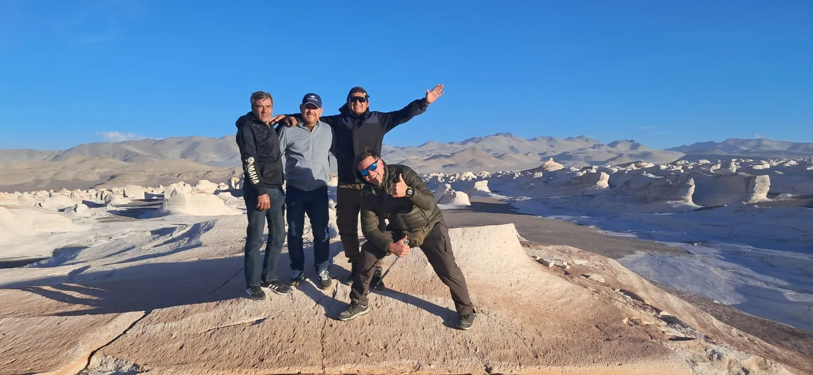 Cuatro viajeros posando al borde de una meseta de piedra pómez, con el campo detrás