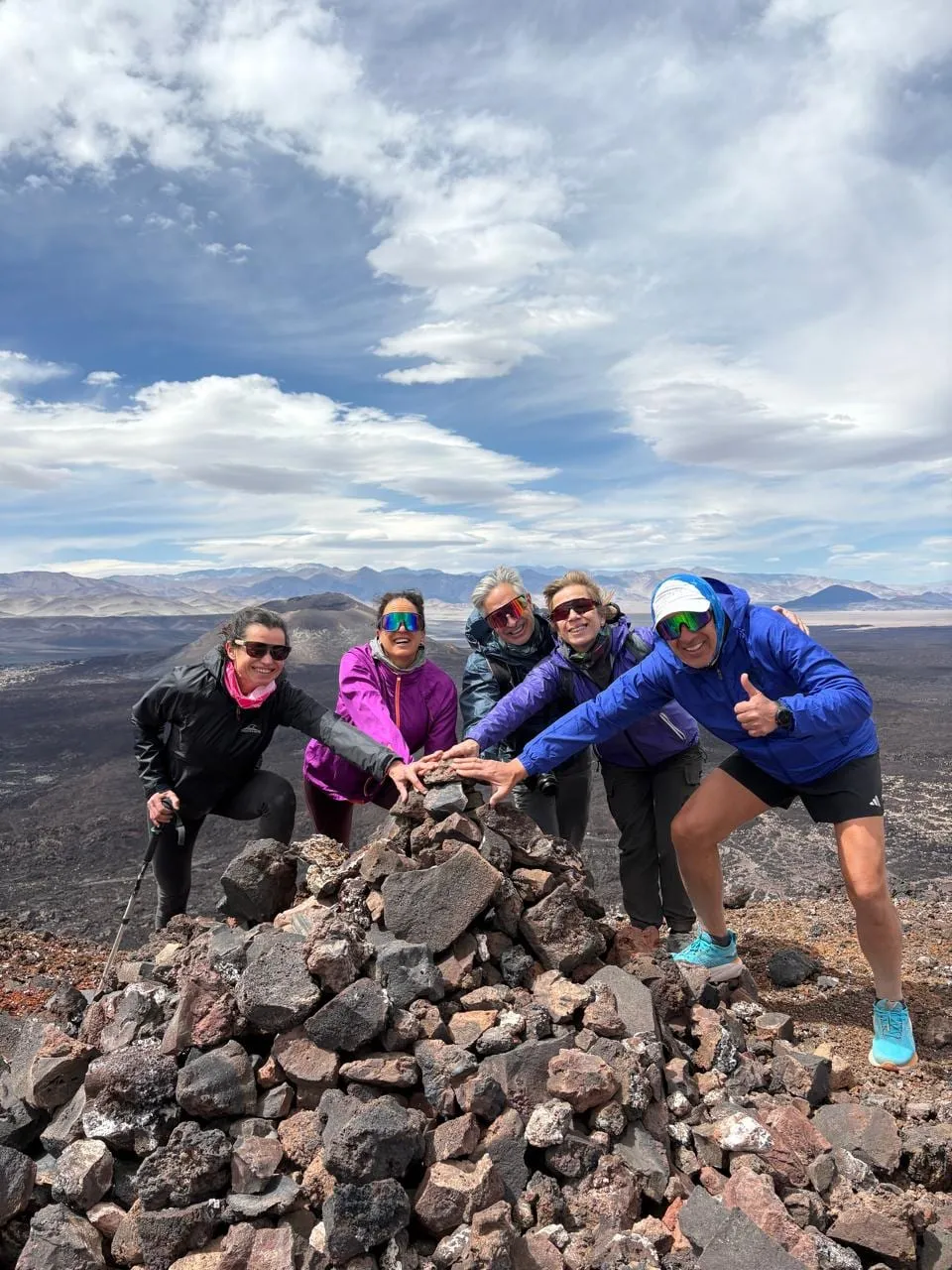 Un grupo de viajeros con bastones, apoyados en un mojón de piedras volcánicas
